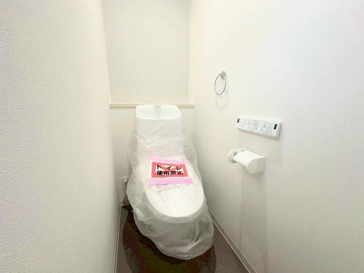 白い壁面と清潔感のあるホワイトの便器をベースに、床面には落ち着いた色合いのタイル調シートを採用。シックでモダンなコントラストが美しく、空間をすっきりと引き締めるデザインです。