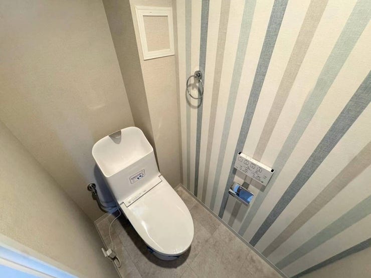 爽やかなストライプ柄のアクセントクロスがスタイリッシュなトイレ空間です。手洗い付きの温水洗浄便座や壁付けリモコンを完備しており、清潔感と使い勝手の良さを兼ね備えています。