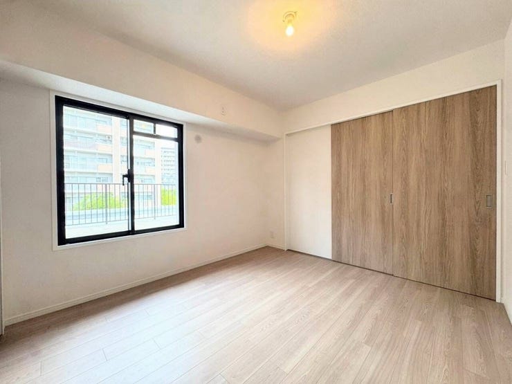 木目の温もりが感じられる扉が印象的な洋室です。窓からの採光で部屋全体が明るく、落ち着いたインテリアに馴染みます。ベッドルームやワークスペースなど、多用途に利用しやすい整った室内です。