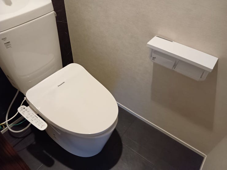 手洗い機能を備えた温水洗浄便座付きのトイレ。凹凸の少ないプレーンなフォルムを採用しており、日々の拭き掃除などのメンテナンスも容易です。