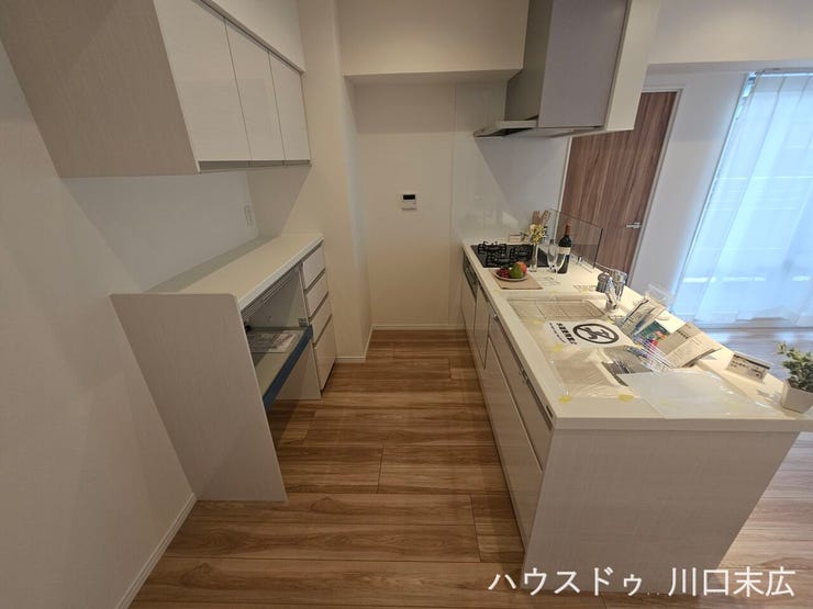 お手入れがしやすいフラットな天板を採用した対面式システムキッチン。背面のカップボードにより、食器や調理器具も整理できます。