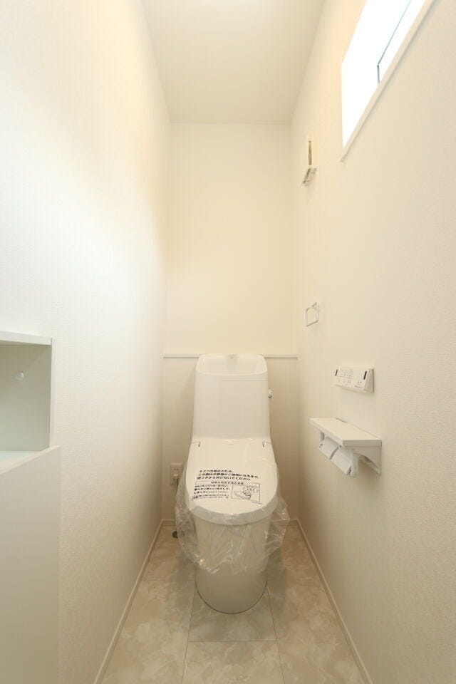 ホワイトの壁紙とタイル調の床が清潔感と落ち着きのある空間を感じさせる1階のトイレです。
停電時、災害時に水が流れやすいタイプのタンク式トイレで、見た目だけでなく実用性・安心性も兼ね備えています。