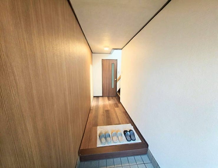 玄関から室内へまっすぐ伸びるすっきりとした廊下動線。奥には扉と階段が配置され、各部屋や上階への移動がスムーズです。靴の脱ぎ履きがしやすいゆとりある土間スペースも魅力です。