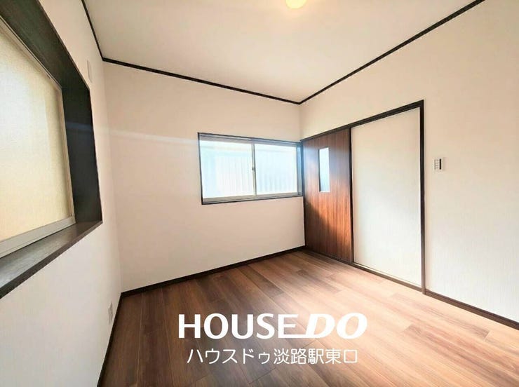 2面に窓を備えた風通しの良い洋室。やわらかな自然光が室内を包み込み、心地よい住環境を創り出します。シックな木目調フロアと黒の枠組みが印象的で、スタイリッシュな佇まいです。