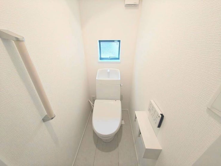 清潔感のある白を基調としたトイレ空間。手洗い付きタンクや手すり、ペーパーホルダー上のカウンターなど実用的な機能が充実。小窓からの採光と換気でいつでも快適に保てます
