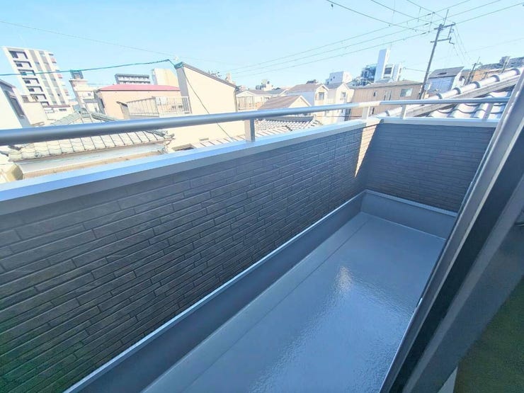 青空が広がり爽やかな風が通り抜けるバルコニー。手すり壁で外からの視線を遮りつつプライバシーに配慮された設計で、洗濯物や布団を干すスペースとしても心地よく活用できます。