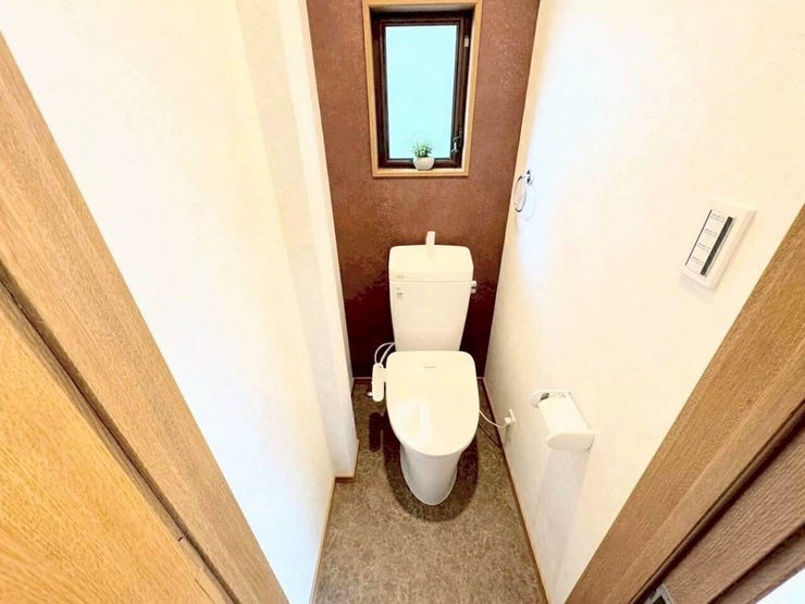 温水洗浄便座が備わった実用的な洋式トイレです。便座脇の手元スイッチでスムーズに操作でき、ペーパーホルダーやタオル掛けが使いやすい位置に配置されているため、日々の使用やお手入れが快適に行えます。