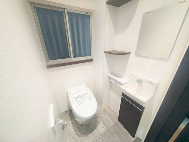 温水洗浄便座と専用の手洗いボウルを備えた衛生的なトイレ空間です。独立した手洗い器があるため、使用後にその場で手を洗うことができ、室内を清潔かつ快適に保持できます。