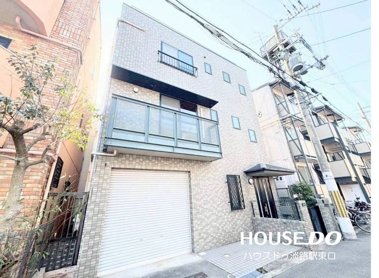 タイル調の外壁と重厚感のあるフォルムが特徴的な3階建て住宅。ビルトインガレージやバルコニー、小さな窓がバランスよく配されたモダンな外観デザインです。