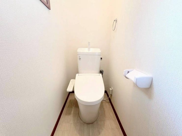 清潔感あふれる白を基調としたシンプルなトイレです。温水洗浄便座や手洗い付きタンクを完備し、快適にご利用いただけます。ペーパーホルダーやタオル掛けも設置されており、スッキリとした印象の空間です。