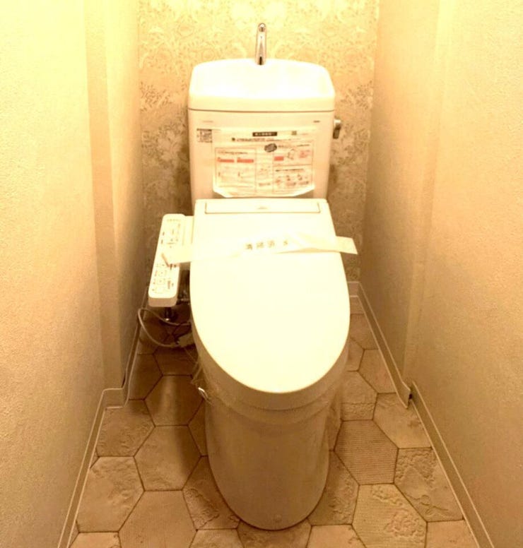 清潔感のある温水洗浄便座付きのトイレです。手洗い付きタンクや操作しやすいパネルなど、使い勝手に優れています。上品な床模様と暖色系の照明が、落ち着いた雰囲気を演出する快適な空間です。
