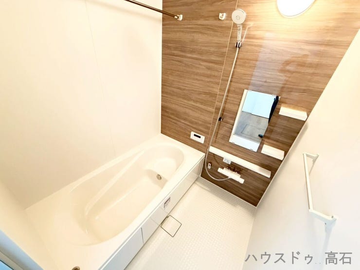 木目調パネルが落ち着いた印象を与えるバスルーム。