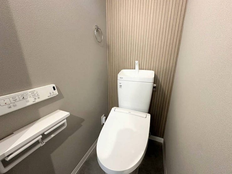背面の木目調アクセントクロスが目を引く、ナチュラルテイストの洗練されたトイレ空間。