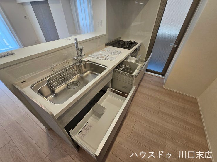 ビルトイン食器洗い乾燥機を備えたシステムキッチン。スライド式の収納は奥の調理器具も取り出しやすく、家事の効率化をサポートする機能的な造りです。