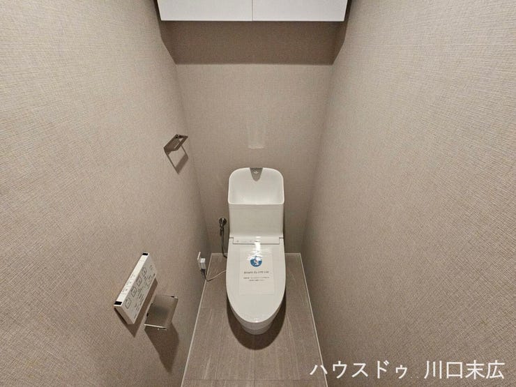 温水洗浄便座を備えた機能的なトイレ空間。上部には手洗い用の吐水口が設けられており、限られたスペースを有効に活用したスマートな設計です。
