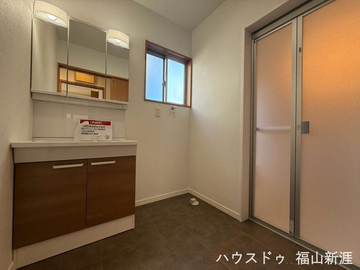 洗面化粧台を備えた洗面脱衣室。窓付きで明るく、洗濯機置場もしっかり確保されています。