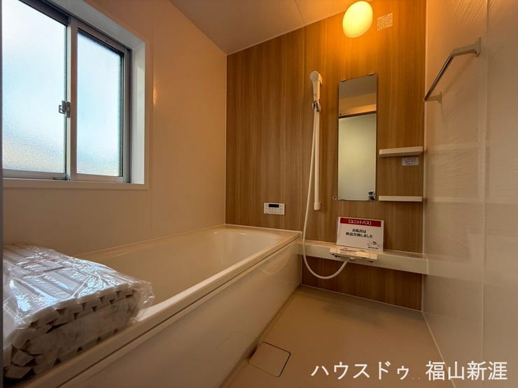 新品交換されたユニットバス。木目調パネルが落ち着いた雰囲気を演出し、一日の疲れをゆっくり癒せます。