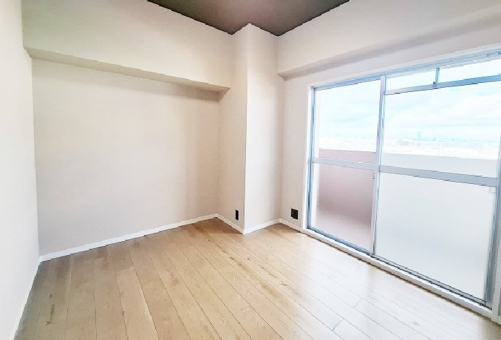 大きな掃き出し窓から光が差し込む明るい洋室。シックなダークカラーの天井クロスがアクセントになり、スタイリッシュな空間を演出しています。