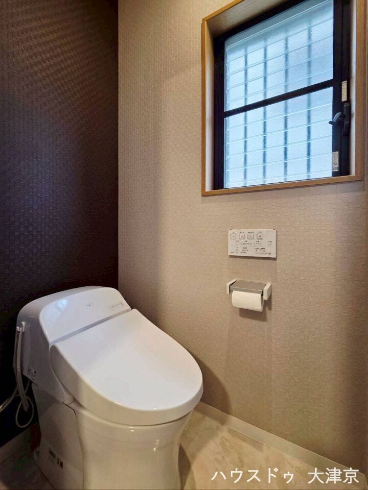 シックなアクセントクロスがおしゃれなトイレ空間。自然光が入る小窓付きで換気・明るさも確保。
