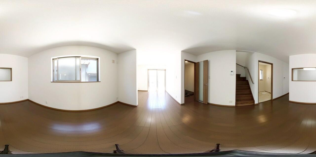白を基調とした壁と、温かみのあるダークブラウンのフローリングが調和した広々としたリビングです。奥の大きな窓からは心地よい光が差し込み、お部屋全体を明るく開放的な雰囲気に演出してくれます。