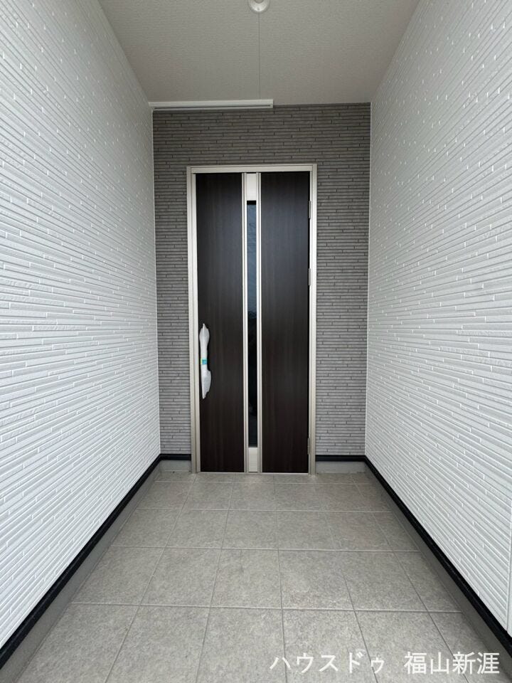 屋根のあるゆったりとした玄関ポーチ。雨の日でも出入りしやすく、落ち着いた色合いの玄関ドアが印象的です
