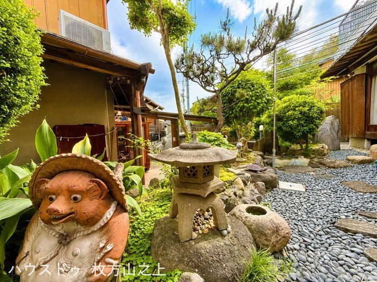 タヌキや石灯篭が迎えてくれるどこか懐かしいお庭。右側に母屋・左側に離れが見えます。