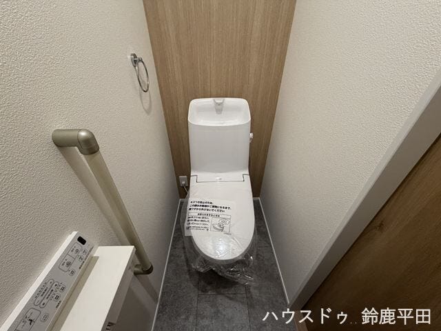 木目調の壁と落ち着いた色の床ですっきりと見えるトイレ空間。手すりも設置されており立ち座りをサポートします。