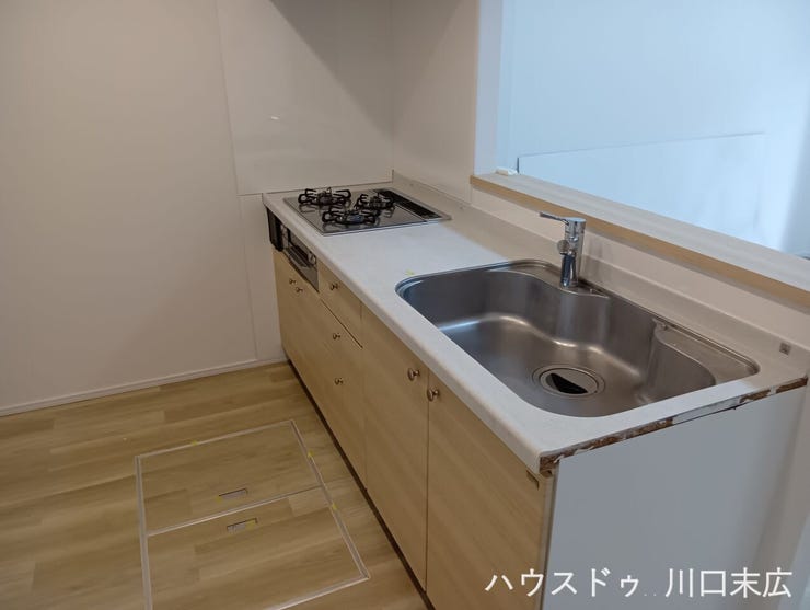 木目調の面材が美しい機能的なシステムキッチン。使い勝手の良いワークスペースを備え、毎日の調理や後片付けをスムーズに行える洗練された設備です。
