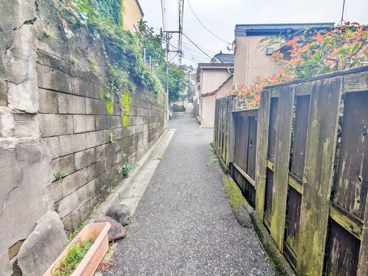 ブロック壁と木製の柵に沿って続く通路です。周辺の雰囲気や階段までの道のりも、歩いて確かめてみませんか。