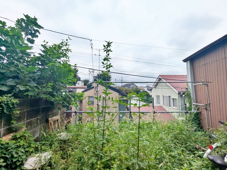 建物脇から見た屋外スペース。草木や周囲の家並みが見えます。現況を確かめながら、土地の使い方をご検討ください。