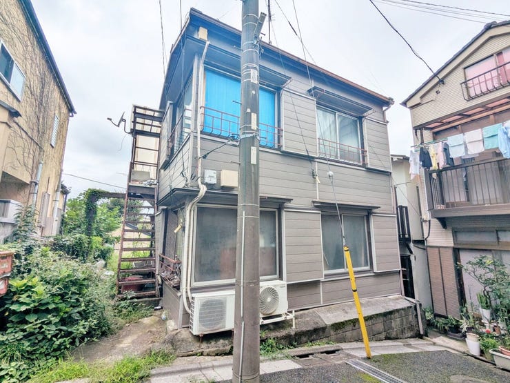 外階段と窓の配置が分かる古家の外観です。建物の状態や敷地との位置関係を、現地でもお確かめください。