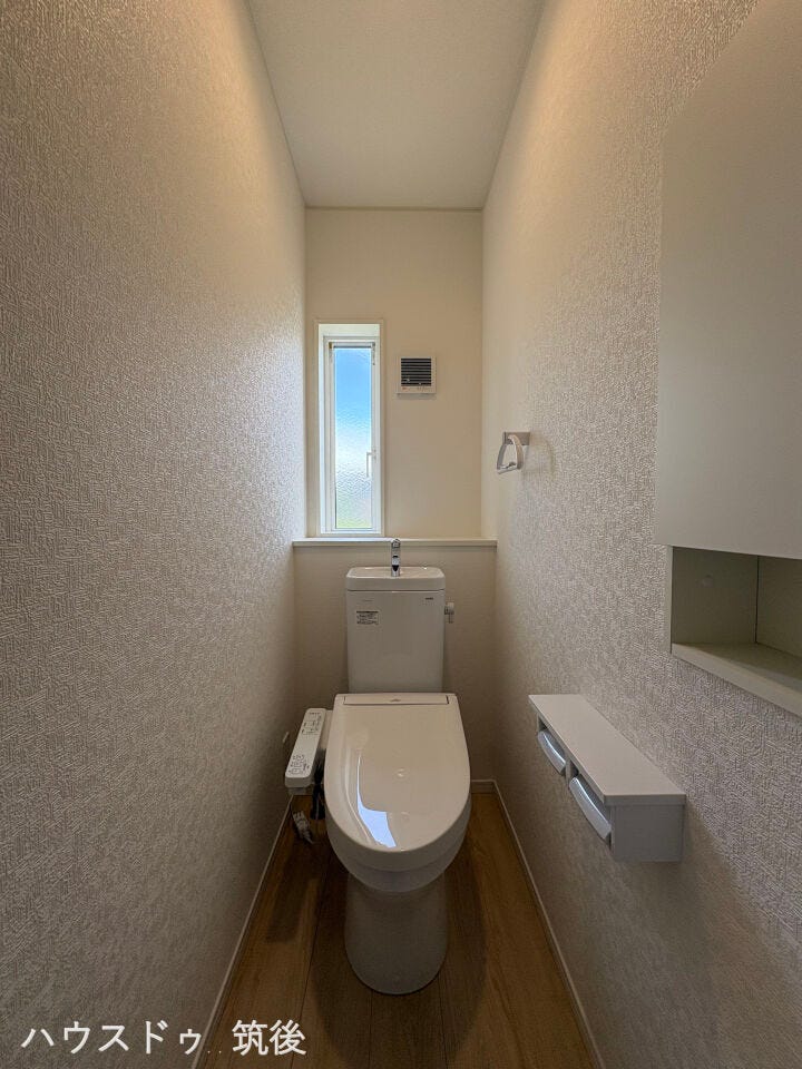 【温水洗浄便座・小窓完備】小窓からの採光と換気もできる明るいトイレ空間!便座横には便利なニッチ収納や棚付きペーパーホルダーを備えています。