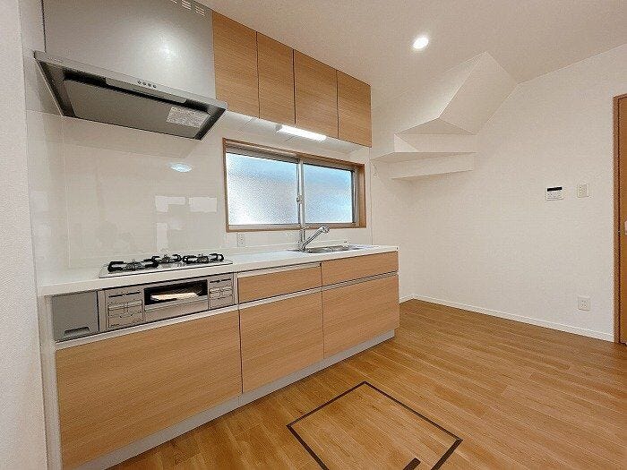 【キッチン】木目調が温かみを演出するシステムキッチン。明るい採光や便利な床下収納を備え、機能性とデザイン性を兼ね備えた快適な調理空間です。